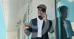 Businessman drinking coffee and talking on mobile phone outside office building