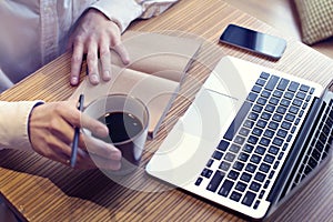 Businessman drinking coffee and working on laptop computer, mobile phone, writing business plan, wearing white shirt