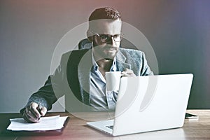 Businessman drinking cup of coffee at laptop