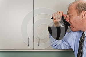 Businessman drinking out of coffee pot