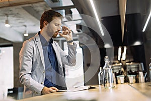 Businessman drinking water and reading paper