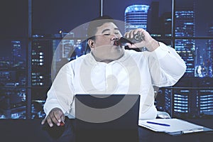 Businessman drinks cola while working overtime