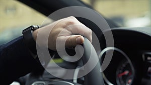 Businessman driving luxury modern car in the city. Stock. Close-up of businessman`s hand driving a car