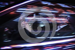 Businessman driving at night, illuminated and reflected lights on the car window