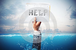 Businessman drowning in the sea with a hand holding a sheet of paper with help written