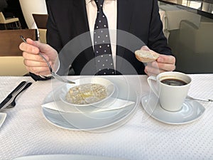 Businessman eating breakfast: a cup of espresso coffee and oatmeal, the concept of proper nutrition. Healthy Breakfast Organic