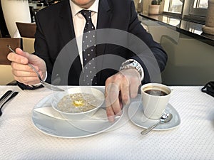 Businessman eating breakfast: a cup of espresso coffee and oatmeal, the concept of proper nutrition. Healthy Breakfast Organic