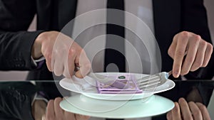 Businessman eating euro banknotes, squandering concept, embezzlement of budget