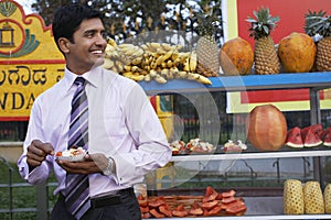 Businessman Eating Fruit Salad At Outdoor Stall