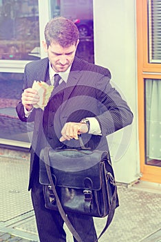 Businessman is eating and looking for time