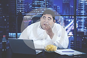 Businessman eating snack while working overtime