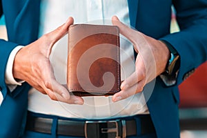 A businessman in an elegant blue jacket and white shirt shows off a leather brown cover for passport. Close-up of the