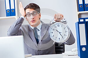The businessman employee in urgency and deadline concept with alarm clock