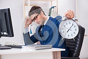 The businessman employee in urgency and deadline concept with alarm clock