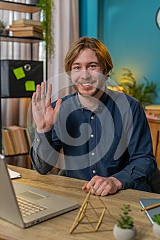 Businessman employee waves hand hello gesture greeting welcomes someone online webinar conversation