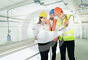 Businessman or engineer architect mixed race young caucasian man and asian woman wear hard hat talking to architects at