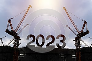 Businessman engineer looking 2023 blueprint in a building site. Silhouette of construction worker with crane and cloudy
