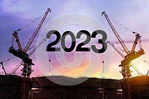 Businessman engineer looking 2023 blueprint in a building site. Silhouette of construction worker with crane and cloudy sky for