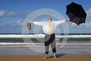 Businessman escaping to a beach vacation, arms outstretched, retirement happiness concept