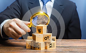 A businessman examines boxes goods with magnifying glass. Market structure research, find unoccupied target consumer niches, photo