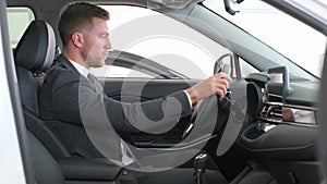 A businessman examines the interior of a new car. Buying a new electric car at a dealership.