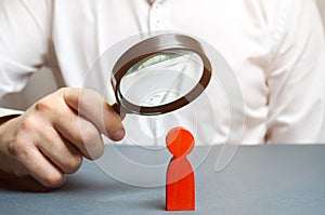 Businessman examines a red man through a magnifying glass. Search for unreliable employee. Weak link. Diagnosis of psychological