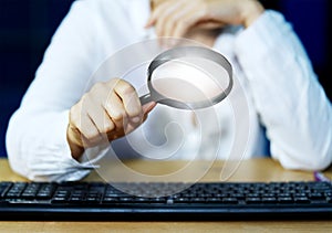 Businessman examining computer equipment with glowing magnifying glass Internet Information Security Concepts select focus on the