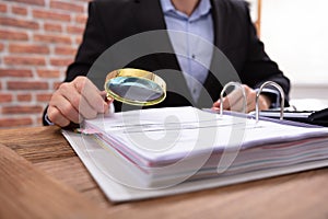 Businessman Examining Invoice Through Magnifying Glass