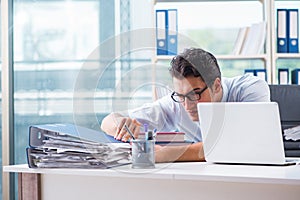 The businessman with excessive work paperwork working in office