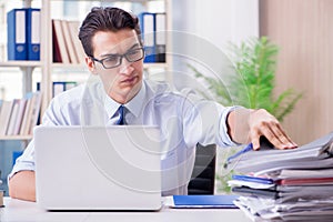 The businessman with excessive work paperwork working in office