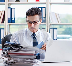 Businessman with excessive work paperwork working in office