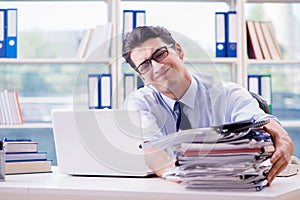 The businessman with excessive work paperwork working in office photo
