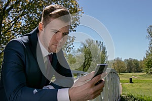 Businessman, Executive in blue suit using mobile, cell phone in the park