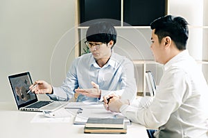 Businessman explaining numeric graphs on computer to colleagues
