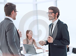 businessman explaining something to his colleague standing in the office.