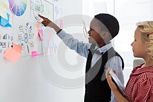 Businessman explaining to female colleague over whiteboard in office