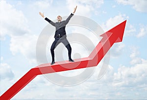 Businessman expressing happy and standing on big red line graph with an upturned arrow