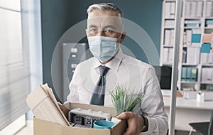 Businessman with face mask leaving the office with his belongings