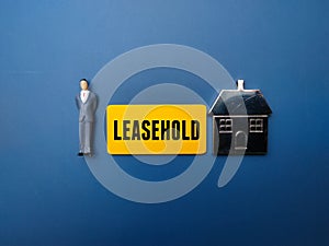 Businessman figurine standing next to a bright yellow sign that reads Leasehold