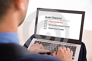 Businessman filling audit checklist form