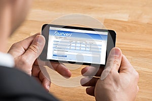 Businessman Filling Online Survey On Mobile Phone