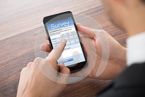 Businessman Filling Online Survey On Mobile Phone photo