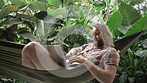 Businessman finishing work on laptop, relaxing on hammock
