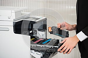 Businessman Fixing Cartridge In Printer Machine At Office photo