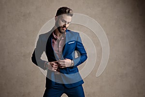 Businessman fixing his jacket while looking down seductive