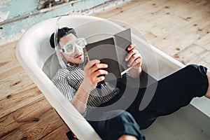 Businessman in flippers and mask lies in bathtub