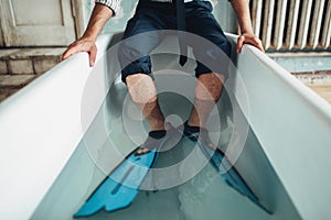 Businessman in flippers sitting in bathtub, humor