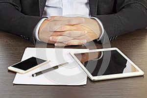 Businessman folded his hands at the desk close-up.