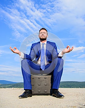 Businessman formal suit sit on briefcase and meditating outdoors. Entrepreneur find minute to relax and meditate. Man