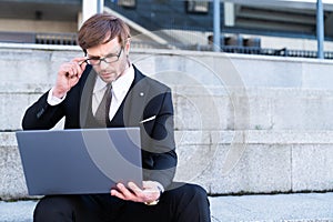 Businessman in formal suit using laptop outdoors